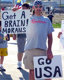 Man holding signs "Get a brain, morans" and "Go USA"