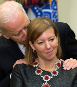 Joe Biden sniffing a woman's hair with his hands on her shoulders