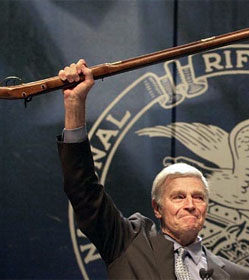 Charlton Heston hoisting rifle before 2000 NRA convention