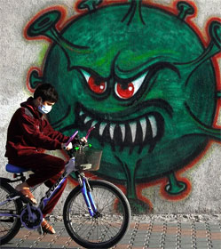 Bicyclist passing street art of Covid germ