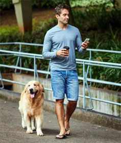 Man walking his dog while staring at his phone