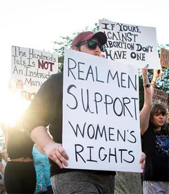 Protesters including man holding "Real Men Support Women's Rights" sign