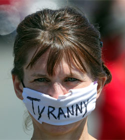 Woman in mask marked "TYRANNY"